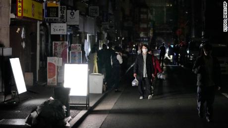Orang-orang berjalan di jalan selama pemadaman listrik di Tokyo.