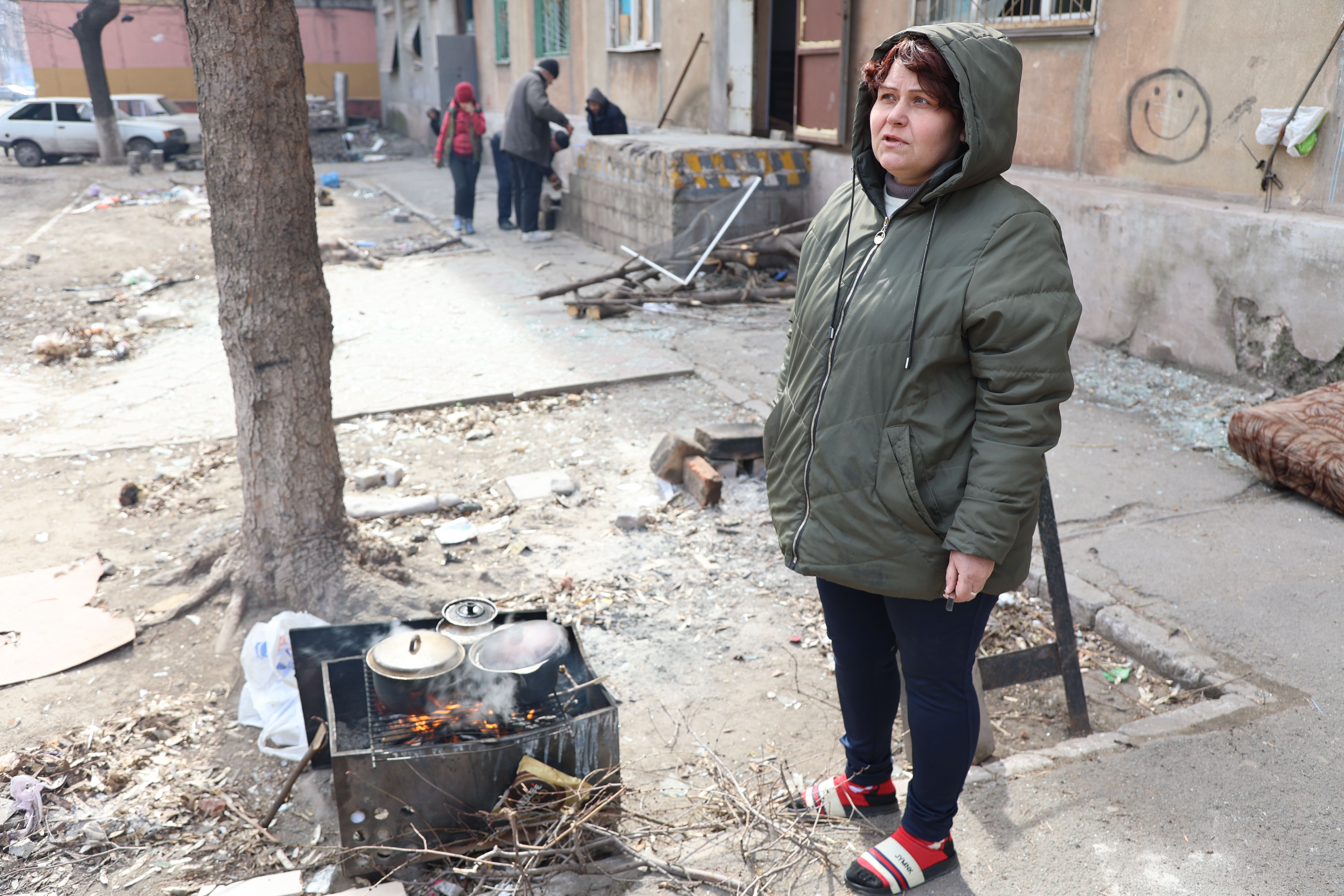 Warga sipil memasak makanan di tengah puing-puing apartemen yang dibom di kota Mariupol, Ukraina, yang berada di bawah kendali tentara Rusia dan separatis pro-Rusia, pada 29 Maret.
