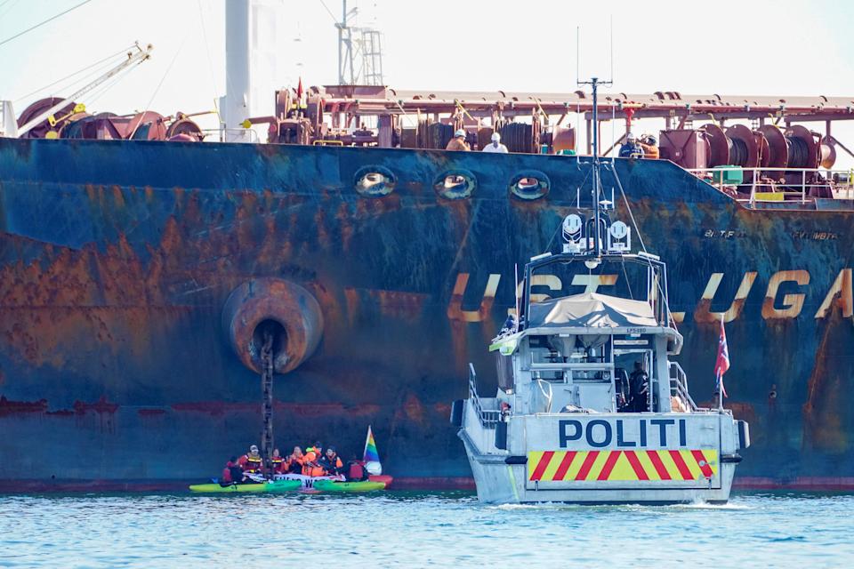 Sebuah kapal polisi berlayar di dekat anggota organisasi Greenpeace yang mencegat sebuah kapal tanker minyak 