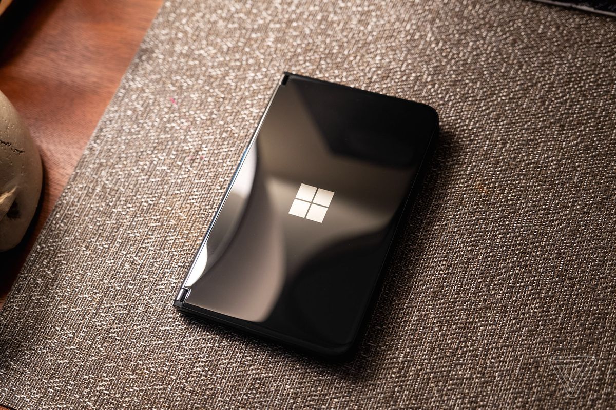 Microsoft Surface Duo 2 hitam tertutup dan duduk di atas kasur.