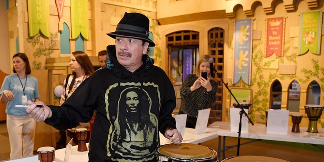Artis Carlos Santana menandatangani tanda tangan kongres yang disumbangkan oleh dia dan istrinya Cindy Blackman Santana ke Las Vegas Philharmonic saat berpartisipasi dalam program pendidikan musik orKIDStra versi global Orkestra Philharmonic untuk sekelompok siswa di Museum Penemuan Anak pada 29 Oktober 2019 di Las Vegas, Nevada.