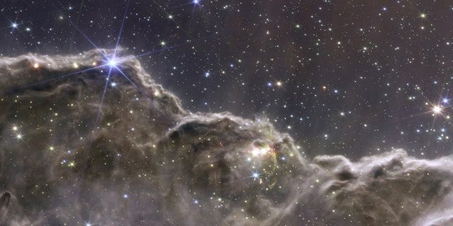 Gambar komposit tebing kosmik di Nebula Carina, dibuat dengan data instrumen NIRCam dan MIRI dari Teleskop Luar Angkasa James Webb NASA, instrumen revolusioner yang dirancang untuk melihat ke seluruh alam semesta hingga fajar alam semesta dan dirilis 12 Juli 2022. 