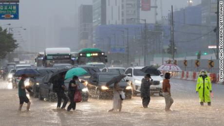 Pejalan kaki melintasi jalan yang banjir di Gimpo, Seoul, pada 9 Agustus.