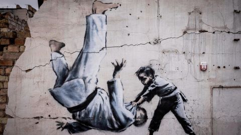 Sebuah mural yang belum diklaim secara resmi oleh Banksy menunjukkan seorang pria berbalik saat pertandingan judo dengan seorang anak laki-laki. 