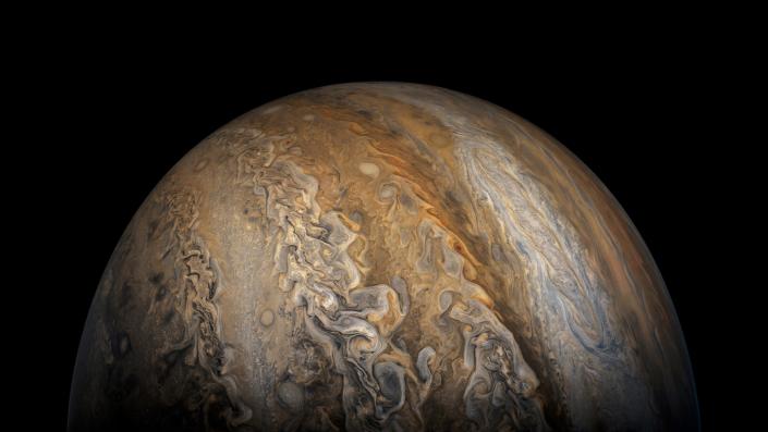 Jupiter terbit dalam kegelapan dengan garis-garis oranye, putih, dan ungu kecokelatan