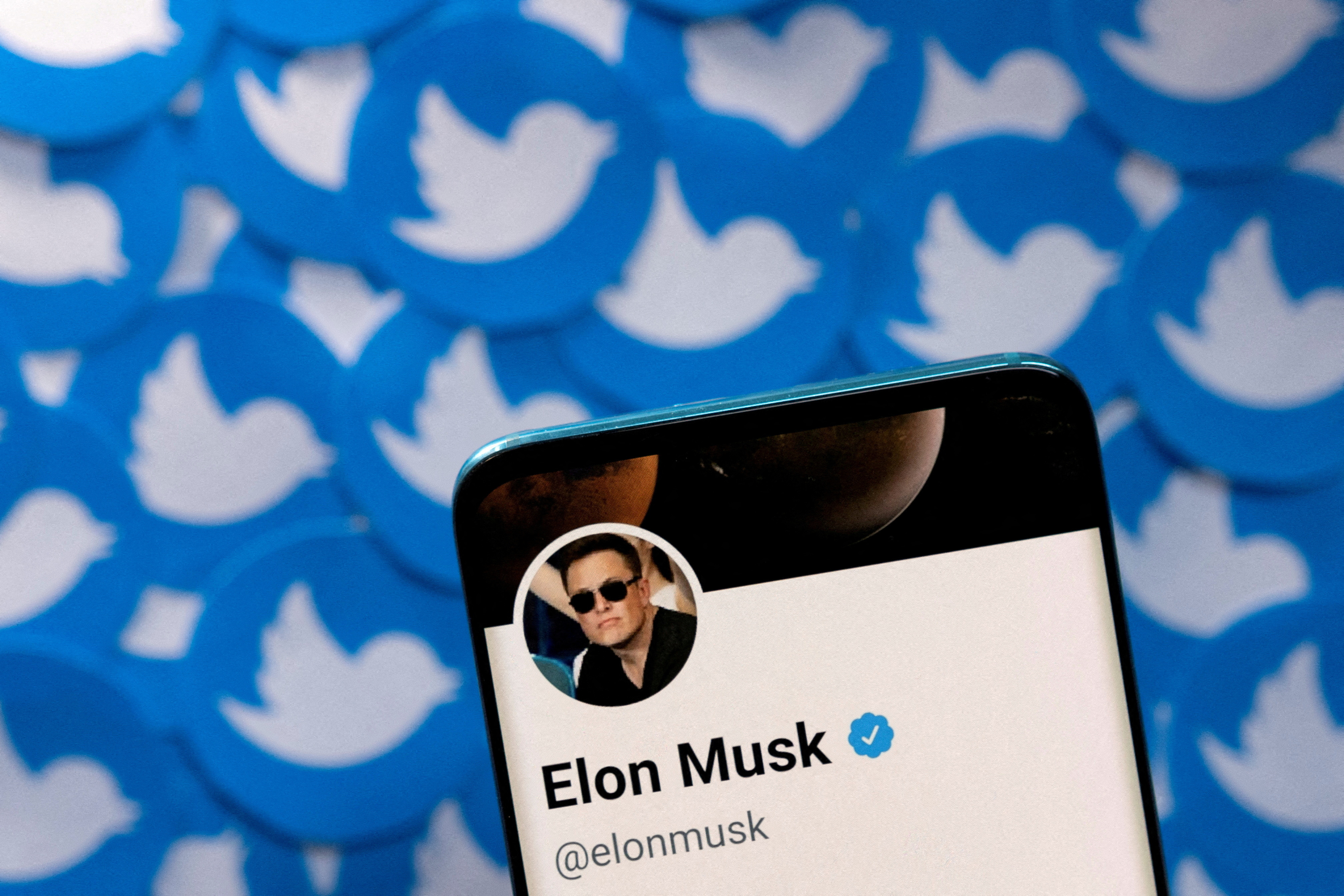 Ilustrasi menunjukkan profil Twitter Elon Musk di smartphone dan logo Twitter dicetak